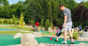 A little boy putts a ball while dad watches