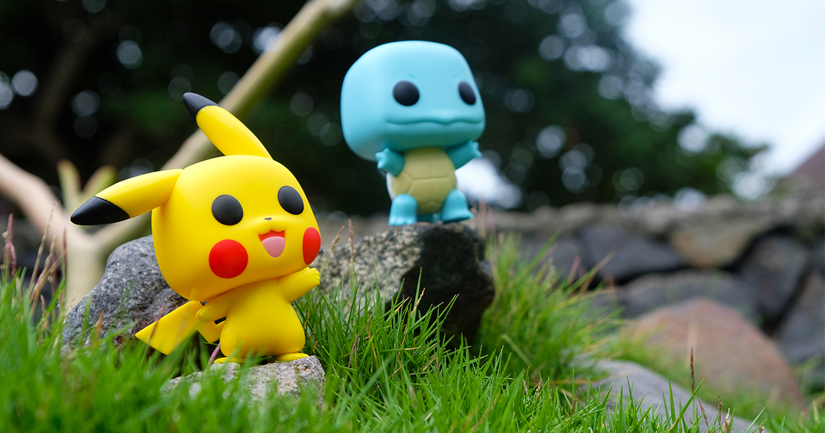 Pikachu and Squirtle funko pops on rocks surrounded by grass